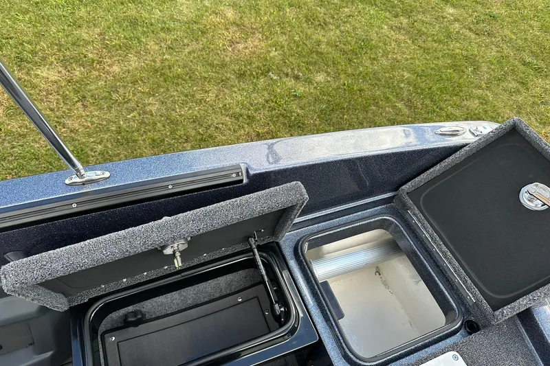Slide: The Image of 2026 Lund 189 Pro-V GL boat storage compartments and livewell on grassy background. - 11