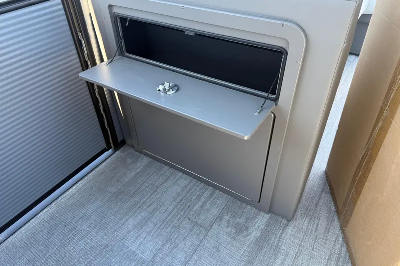 Slide: The Image of 2026 Qwest E-Class 22 Lanai interior storage compartment with fold-down shelf. - 16