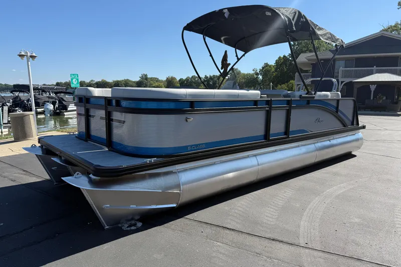 Slide: The Image of 2026 Qwest E-Class 22 Lanai pontoon boat docked near a marina. - 2