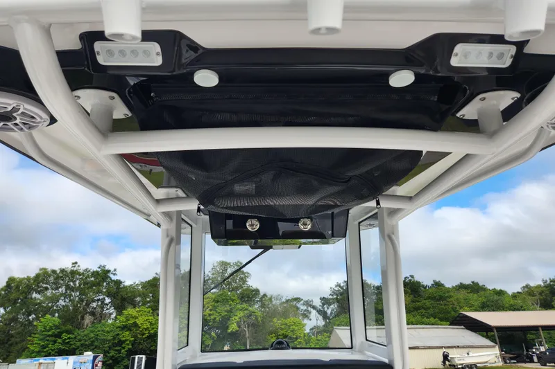 Slide: The Image of 2026 Caymas 291 boat interior, featuring overhead storage and lighting against a cloudy sky backdrop. - 26