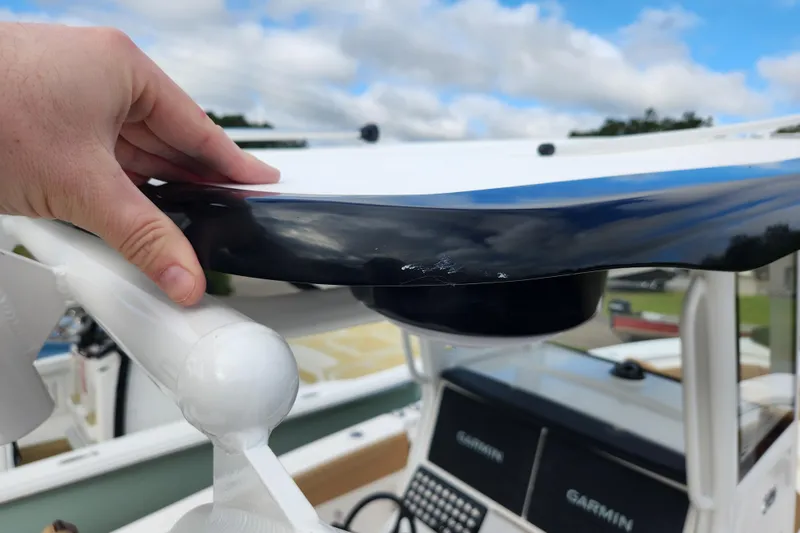 Slide: The Image of Hand inspecting Caymas 291 boat component, showcasing Garmin equipment, under a cloudy sky. - 50