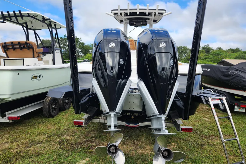 Slide: The Image of 2026 Caymas 291 boat with dual outboard engines, parked on grass. - 52