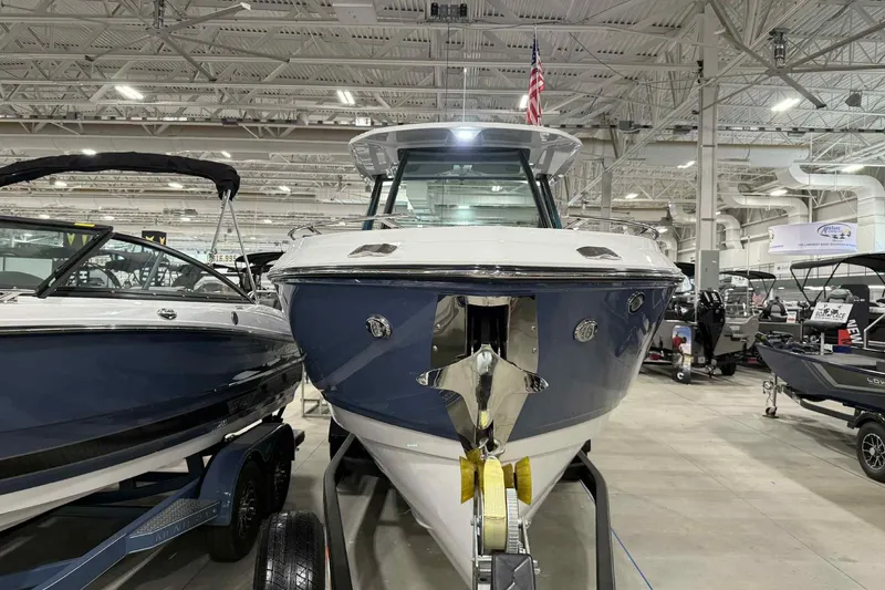 Slide: The Image of 2026 Monterey Elite 27 SD boat displayed in a showroom with other boats. - 2