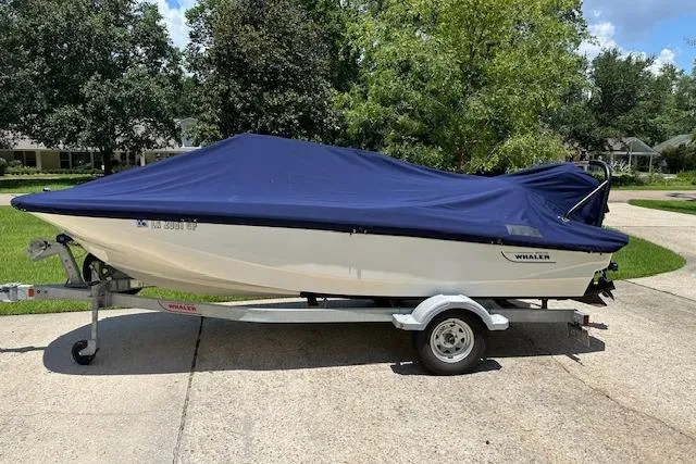 Slide: The Image of 2022 Boston Whaler 160 Super Sport boat covered on trailer, parked outdoors. - 12