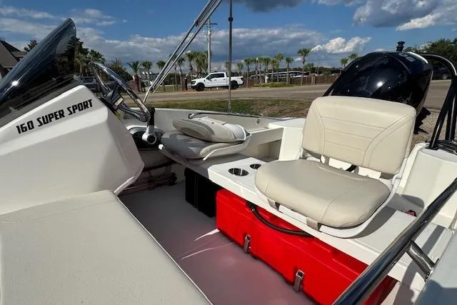 Slide: The Image of 2022 Boston Whaler 160 Super Sport interior with seating and storage, under a partly cloudy sky. - 20