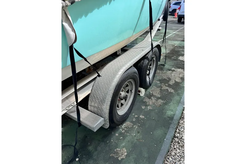 Slide: The Image of Trailer with 2017 Tidewater 220 CC Adventure boat, secured with straps, parked on pavement. - 17