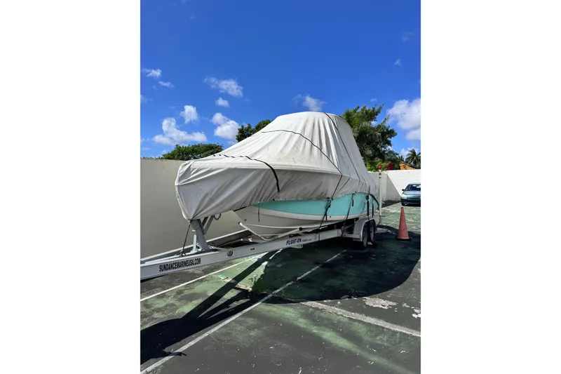 Slide: The Image of 2017 Tidewater 220 CC Adventure boat covered on trailer under blue sky. - 18