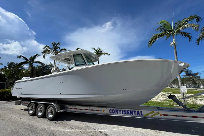 Slide: The Image of 2026 Sailfish 360 CC boat on trailer under clear blue sky with palm trees. - 4