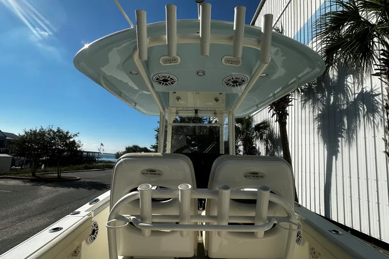 Slide: The Image of 2022 Cobia 262 Center Console boat with rod holders and speakers, docked under clear sky. - 5
