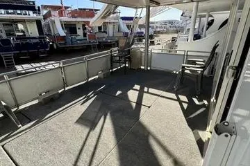 Slide: The Image of 2013 Bravada Bella Luna houseboat deck with chairs, marina view, and shaded seating area. - 2
