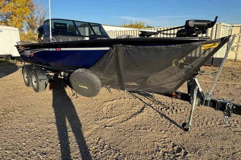 Slide: The Image of 2017 Alumacraft Competitor 205 Sport boat on trailer, parked on gravel. - 2