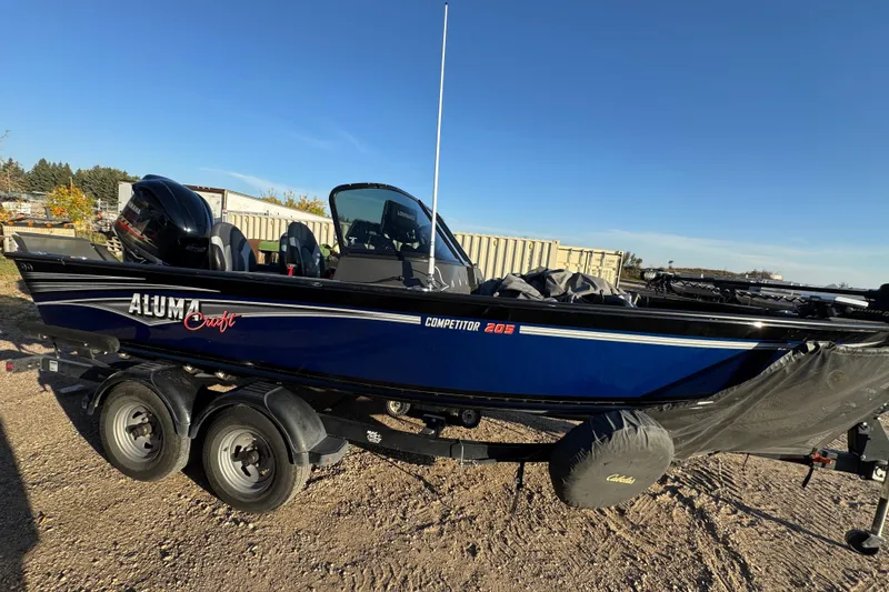 Slide: The Image of 2017 Alumacraft Competitor 205 Sport boat on trailer, parked outdoors under clear blue sky. - 3