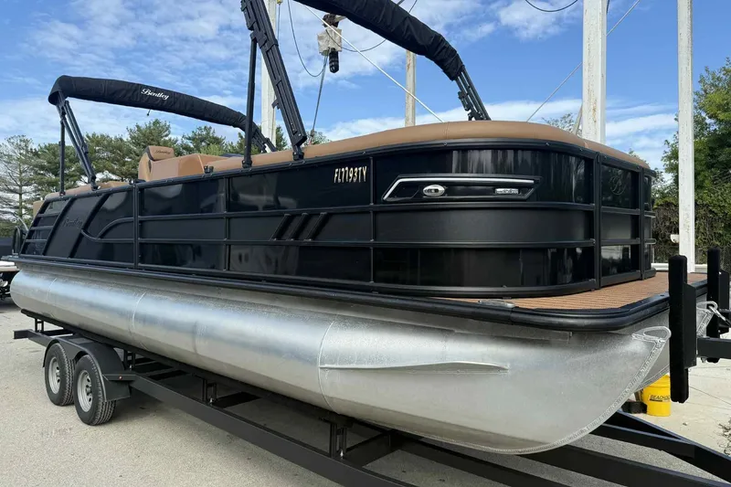 Slide: The Image of 2025 Bentley Pontoons Elite 253 Admiral on trailer, sleek black design, under blue sky. - 6