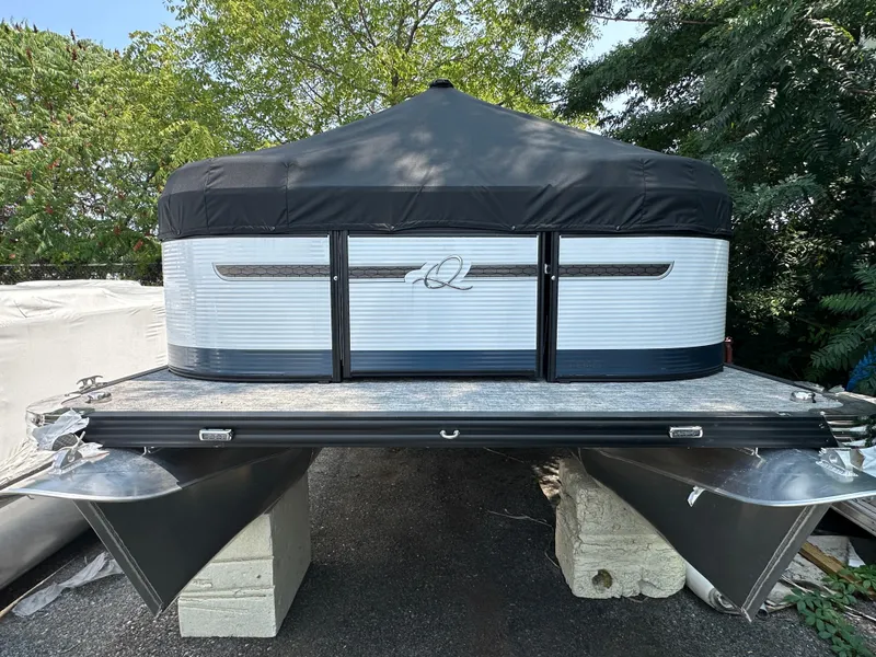 Slide: The Image of 2023 Qwest E 816 Lanai LT pontoon boat with black canopy, parked on blocks. - 1