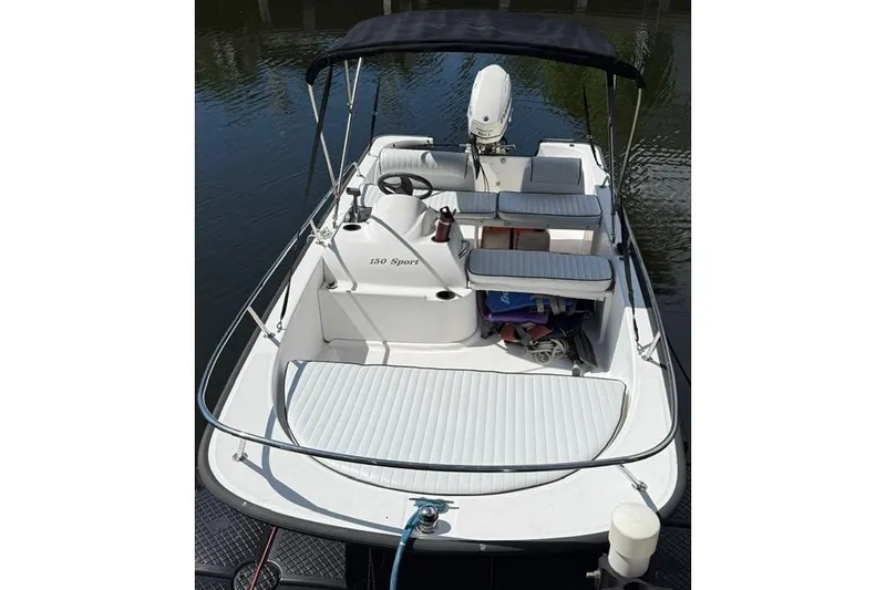 Slide: The Image of 2006 Boston Whaler 150 Sport boat with seating and canopy on calm water. - 17