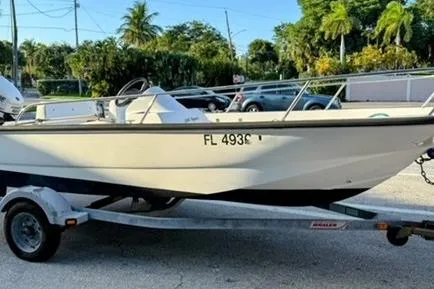 Slide: The Image of 2006 Boston Whaler 150 Sport boat on trailer, parked outdoors with tropical background. - 18