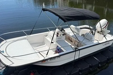 Slide: The Image of 2006 Boston Whaler 150 Sport boat with canopy, docked on calm water. - 19