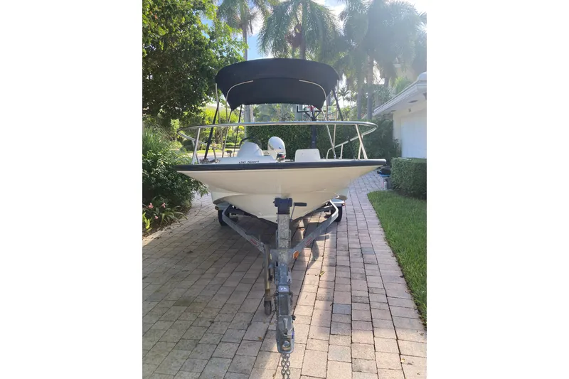 Slide: The Image of 2006 Boston Whaler 150 Sport boat on trailer, parked on a brick driveway. - 2
