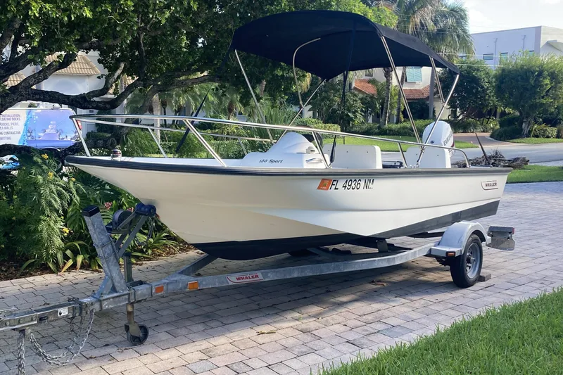Slide: The Image of 2006 Boston Whaler 150 Sport boat on trailer, parked on a paved driveway. - 3