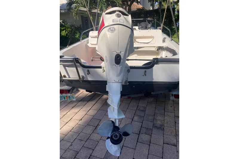Slide: The Image of 2006 Boston Whaler 150 Sport boat with outboard motor on a paved driveway. - 5