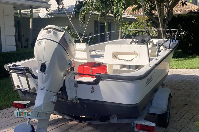 Slide: The Image of 2006 Boston Whaler 150 Sport boat on trailer, parked in driveway. - 7