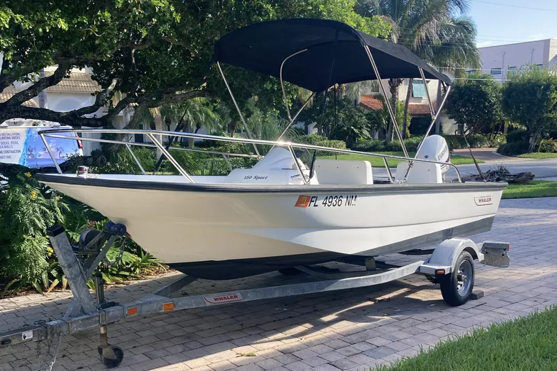 Slide: The Image of 2006 Boston Whaler 150 Sport boat on trailer with canopy, parked outdoors. - 8