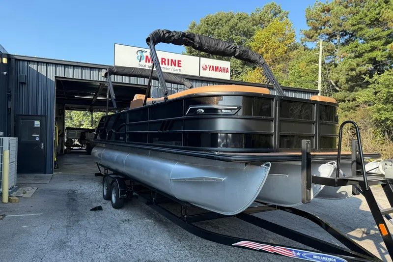 Slide: The Image of 2025 Bentley Pontoons Elite 253 Swingback on trailer outside marine service center. - 1