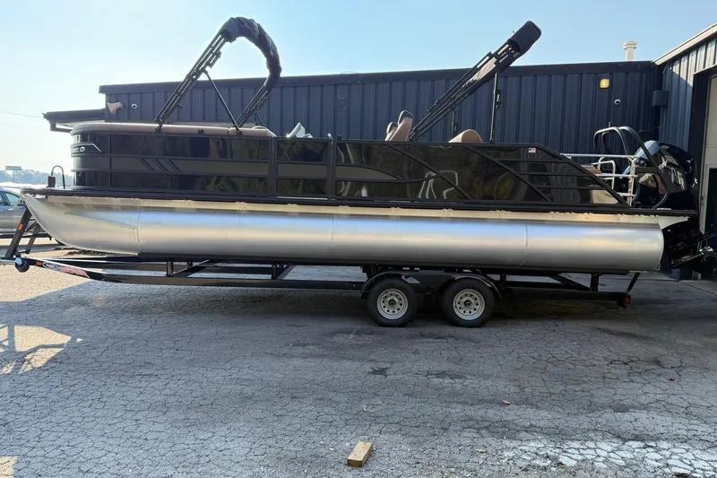 Slide: The Image of 2025 Bentley Pontoons Elite 253 Swingback on trailer, parked outside a building. - 4