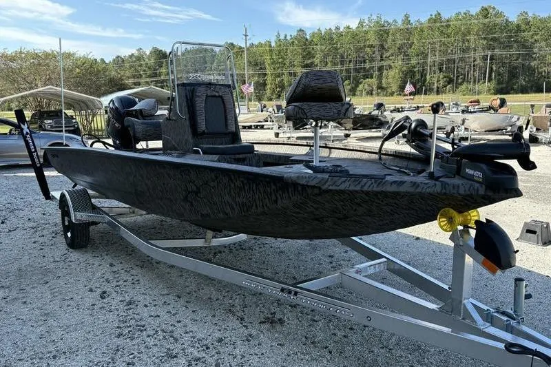 Slide: The Image of 2026 Xpress H20B Bay boat on trailer, parked outdoors with trees in background. - 15