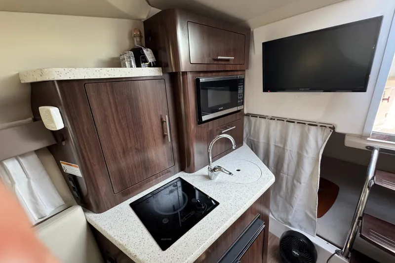 Slide: The Image of 2018 Regal 28 Express boat interior with kitchenette, microwave, and TV. - 13