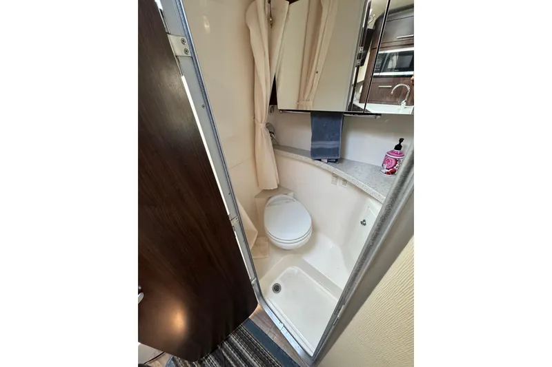 Slide: The Image of 2018 Regal 28 Express boat bathroom with toilet, shower, and mirror cabinet. - 21