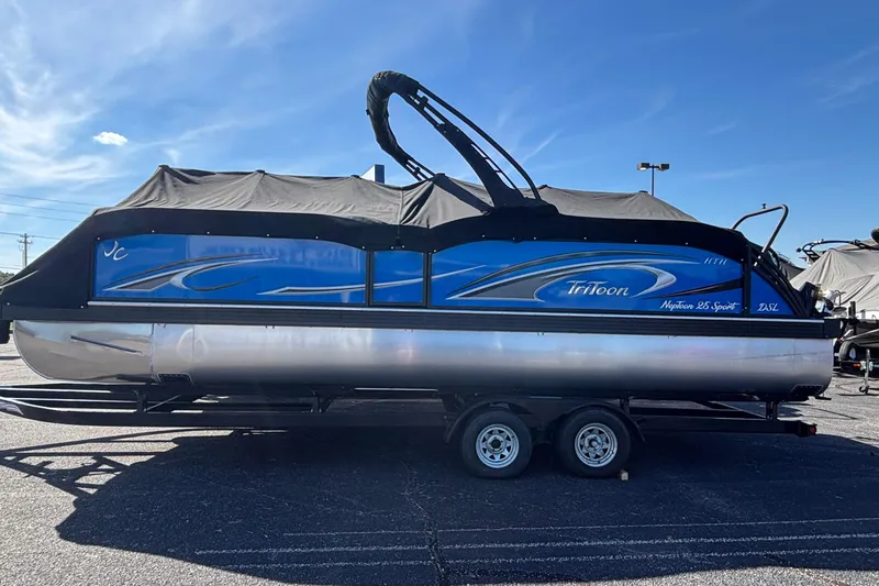 Slide: The Image of 2026 JC Neptoon 25TT Sport pontoon boat with blue and black design on a trailer. - 6