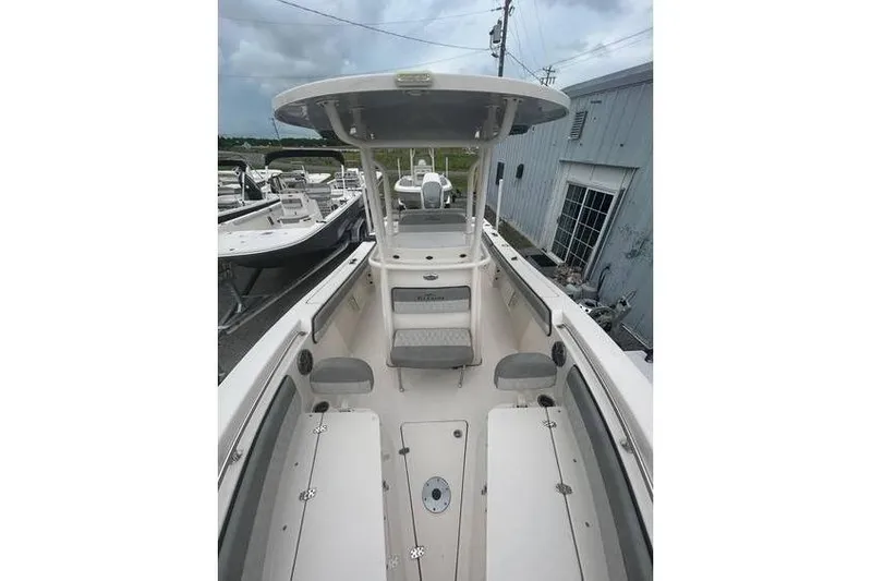 Slide: The Image of 2024 Sea Chaser 24 HFC boat interior with seating and console, docked near a building. - 2