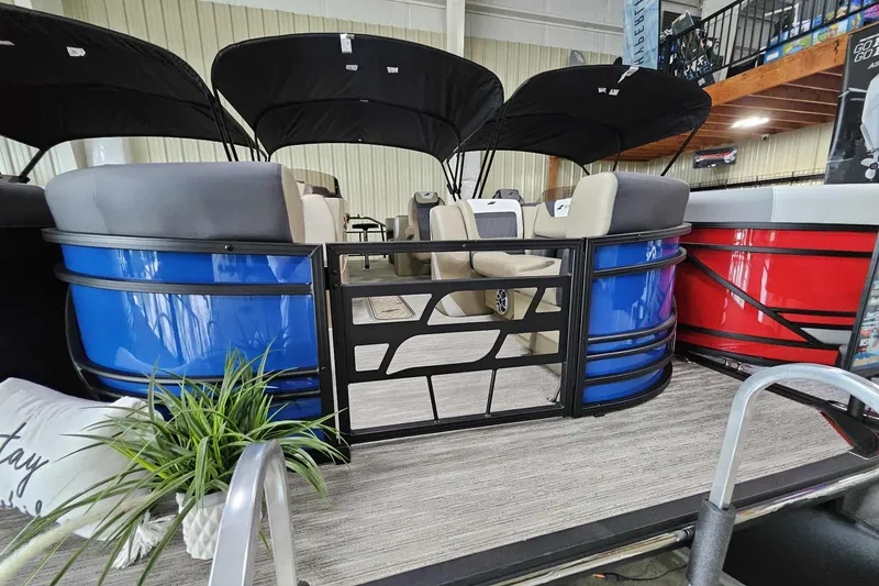 Slide: The Image of 2026 Starcraft SLS 3 R pontoon boat with blue and red exterior, indoor display. - 12