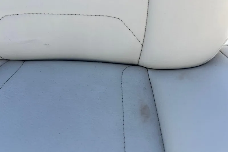 Slide: The Image of 2023 Boston Whaler 130 Super Sport seat detail with white and gray upholstery. - 18