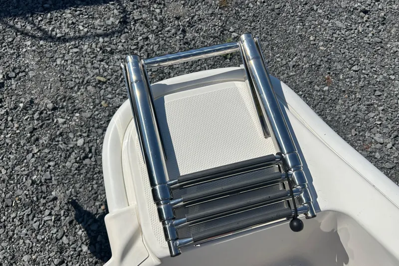 Slide: The Image of Stainless steel ladder on 2023 Boston Whaler 130 Super Sport boat, resting on gravel. - 19