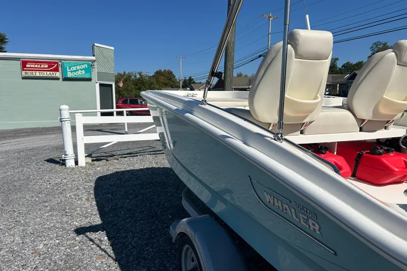 Slide: The Image of 2023 Boston Whaler 130 Super Sport boat parked near dealership, sunny day. - 24