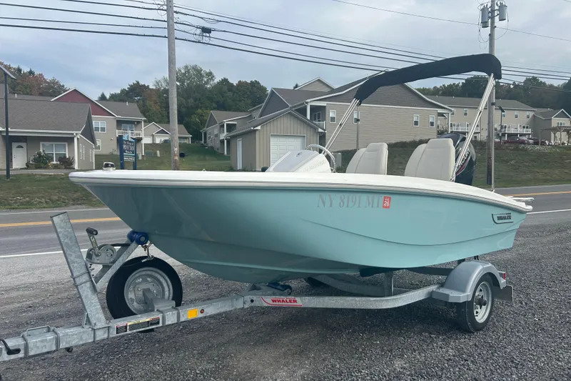 Slide: The Image of 2023 Boston Whaler 130 Super Sport boat on trailer, parked near residential area. - 4