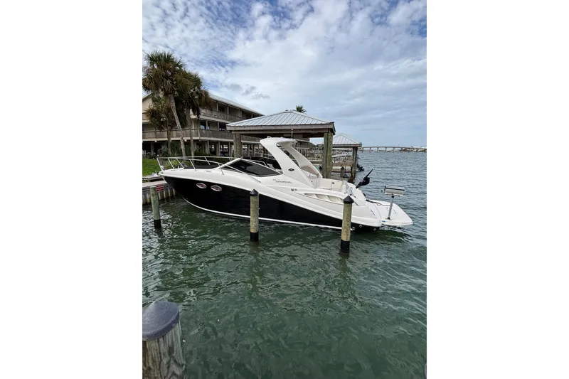 Slide: The Image of 2008 Sea Ray 290 Sundancer docked by waterfront, under a partly cloudy sky. - 16
