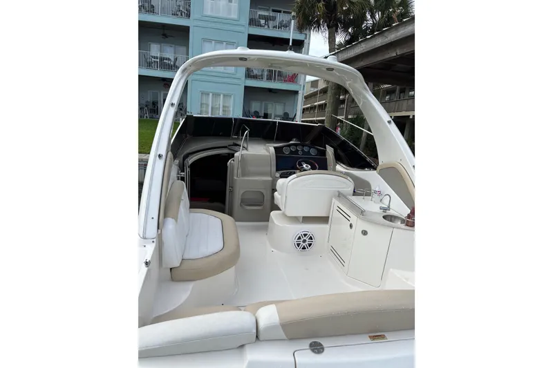 Slide: The Image of 2008 Sea Ray 290 Sundancer boat interior with seating and helm, docked near buildings. - 18