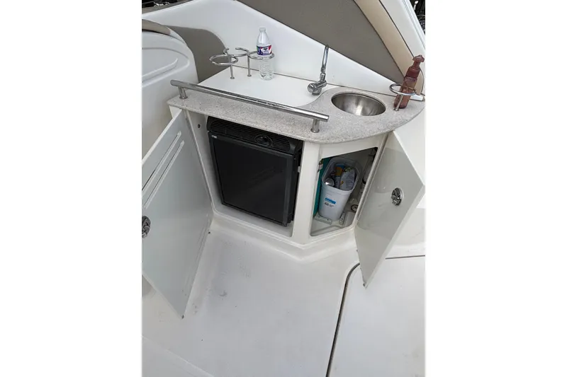 Slide: The Image of 2008 Sea Ray 290 Sundancer boat kitchenette with sink, mini fridge, and storage cabinets. - 19