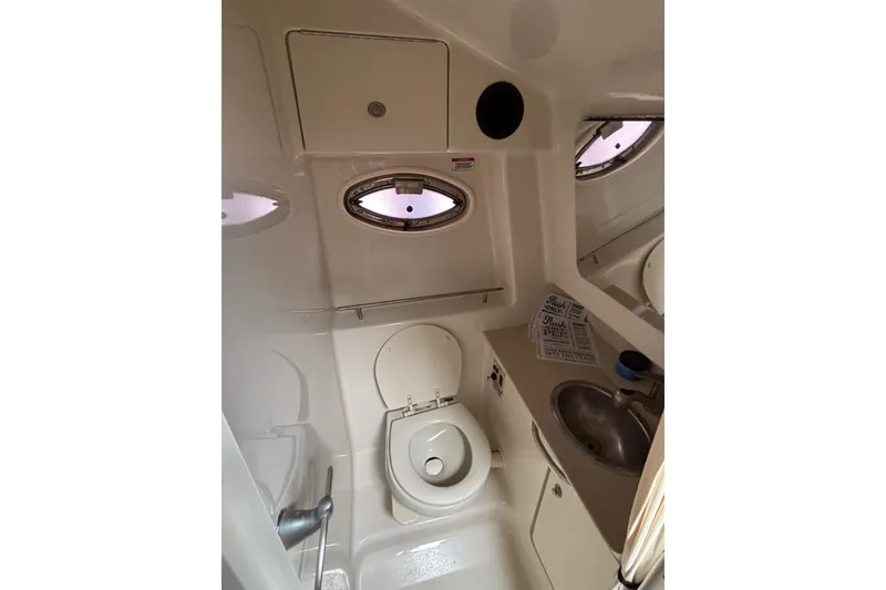 Slide: The Image of 2008 Sea Ray 290 Sundancer boat bathroom with toilet, sink, and porthole windows. - 23