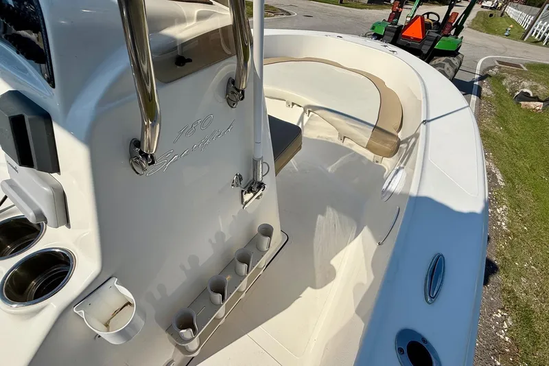Slide: The Image of 2020 Pioneer 180 Sportfish boat interior with seating and cup holders, parked outdoors. - 13