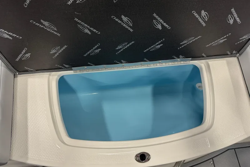 Slide: The Image of Storage compartment in 2026 Chaparral 21 SSi boat, featuring a blue interior and branded cover. - 21