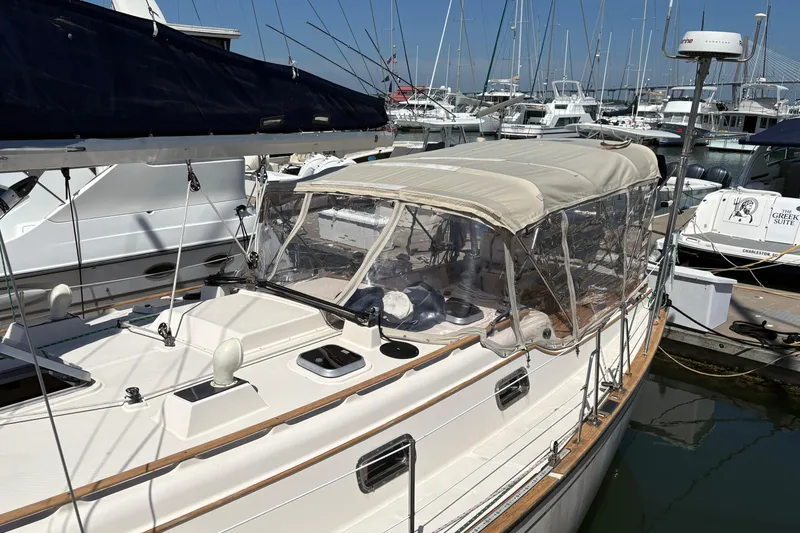 Slide: The Image of 1995 Island Packet 40 sailboat docked at marina, featuring a beige canopy and sleek design. - 11