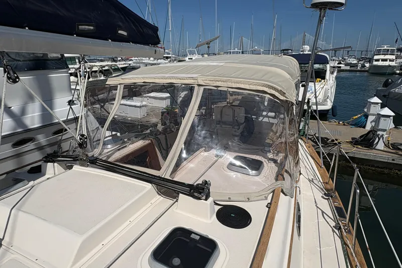 Slide: The Image of 1995 Island Packet 40 sailboat docked at marina, featuring a covered cockpit and clear enclosure. - 13