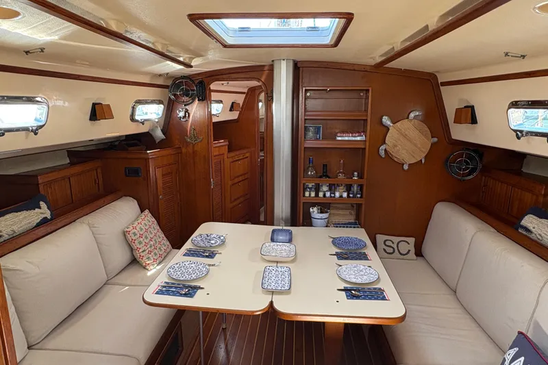 Slide: The Image of Interior of a 1995 Island Packet 40 sailboat with dining setup and cozy seating. - 27