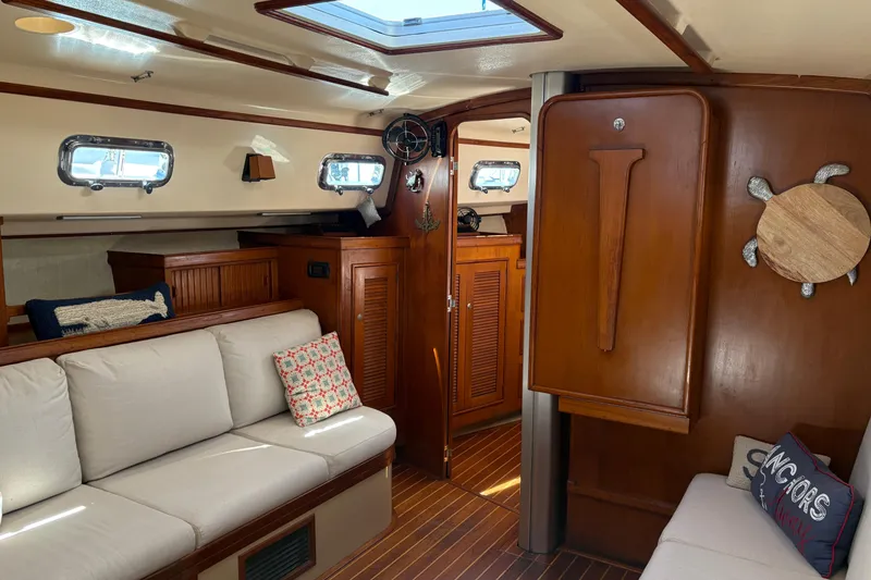 Slide: The Image of Interior of a 1995 Island Packet 40 sailboat with cozy seating and wooden accents. - 29