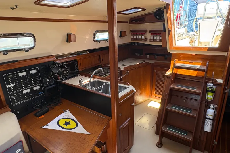 Slide: The Image of Interior of a 1995 Island Packet 40 sailboat, featuring a compact kitchen and navigation area. - 31