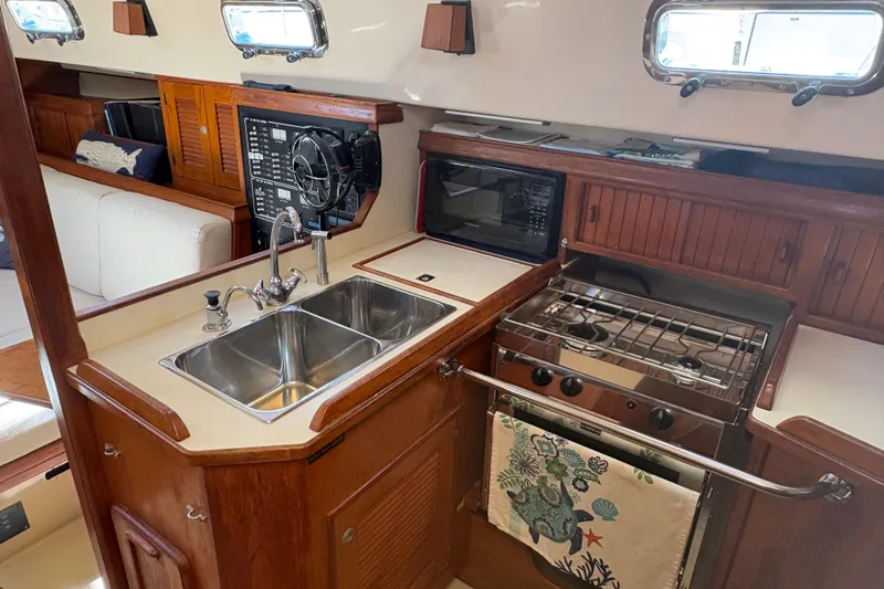 Slide: The Image of Interior of 1995 Island Packet 40 sailboat kitchen with sink, stove, and microwave. - 33